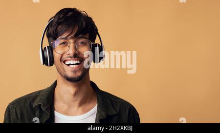 Lachender arabischer Kerl, der sich mit dem brandneuen schnurlosen Headset Vergnügen kann Stockfoto