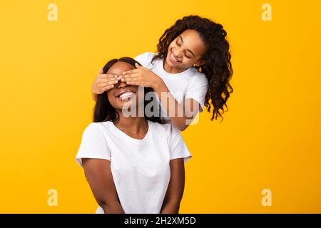 Afroamerikanische Tochter, die im Studio die Augen ihrer Mutter bedeckt Stockfoto