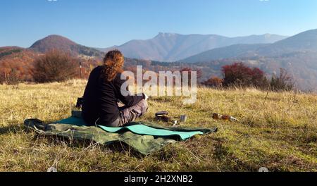 Mann, der auf der Wiese sitzt und herbstliche Sicht auf den Berg Klak, Mala Fatra aus Strazovske vrchy, Slowakei Stockfoto