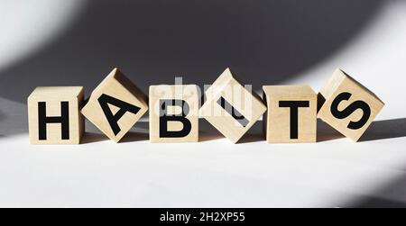 Das Wort Gewohnheiten auf Holzwürfeln und weißem Hintergrund geschrieben Stockfoto