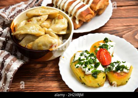 Köstliche hausgemachte Snacks Knödel. Ukrainische Küche Knödel mit Füllung, Pfannkuchen mit Fleisch und saurer Rahm, Kartoffeltortillas mit Hackfleisch Stockfoto