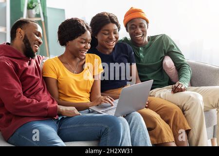 Positive afroamerikanische Millennials sehen lustige Videos auf dem Computer Stockfoto
