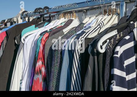 Gebrauchte Second-Hand-Kleidung an Kleiderbügeln auf einem Kleiderständer, als Spende für eine Wohltätigkeitsorganisation oder für den Flohmarkt-Verkauf, ausgewählter Fokus, enge Schärfentiefe Stockfoto