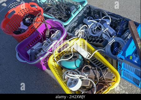 Gebrauchte Elektrokabel und Steckdosenleisten in bunten Kunststoffkörben auf der Straße auf einem Flohmarkt oder einem Garagenverkauf, ausgewählter Fokus, enge Fie-Tiefe Stockfoto