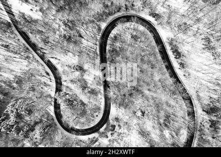 Klare Sicht auf eine Landstraße von oben in der Wintersaison mit viel Schnee, wie von oben nach unten von einer Drohne geschossen. Stockfoto