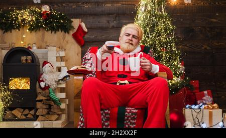 Der weihnachtsmann sitzt im Sessel und trinkt Kaffee. Frohe Weihnachten. Werbung für das neue Jahr Stockfoto