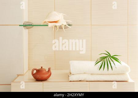 Badetücher, Muschel und Keramikkessel im Badezimmer Stockfoto
