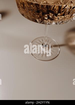 Nahaufnahme eines Kristallglases mit Champagner, der auf einem weißen Holztischhintergrund blinkt Stockfoto