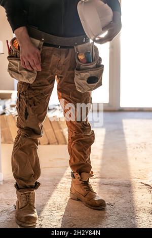 Ein Mann Baumeister hält einen Schutzhelm in seinen Händen, Teil des Körpers. Stockfoto