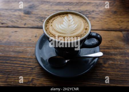 Cappuccino wird auf einem Holztisch in der Cafeteria serviert Stockfoto