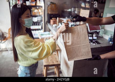 Der Kellner gab den Gästen im Café verpackte Speisen zum Mitnehmen Stockfoto