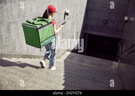 Zustelldienst-Mitarbeiter, der die Bestellung über das Mobiltelefon im Freien überprüft Stockfoto