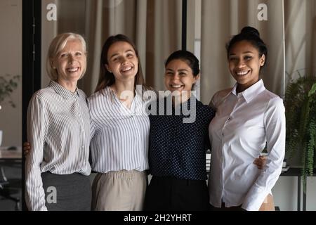 Porträt von vier attraktiven Geschäftsfrauen stehen in Reihe Umarmung Lächeln Stockfoto
