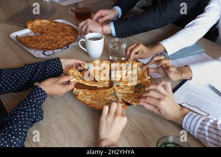 Kollegen verschiedener Geschäftsleute, die in der Mittagspause am Arbeitsplatz Pizza essen Stockfoto