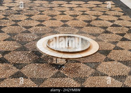 Arabischer Brunnen, in einem Innenhof mit Orangenbäumen, wo er vor einigen Jahrhunderten funktionierte, in einer alten Moschee in Andalusien (Spanien). Stockfoto