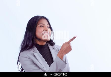 Eine junge lächelnde Frau zeigt etwas mit ihrem Finger Stockfoto
