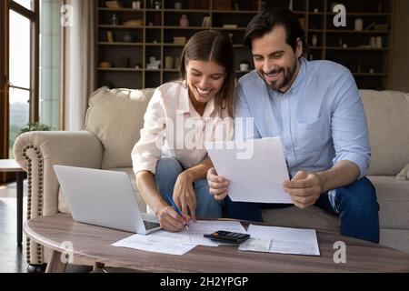 Glückliches, junges Familienpaar, das das Haushaltsbudget verwaltet. Stockfoto