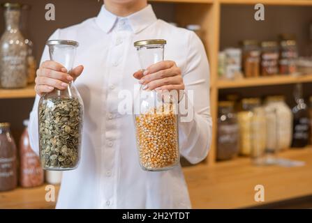 Eine Frau hält zwei Gläser Getreide. Eco-Shop. Stockfoto