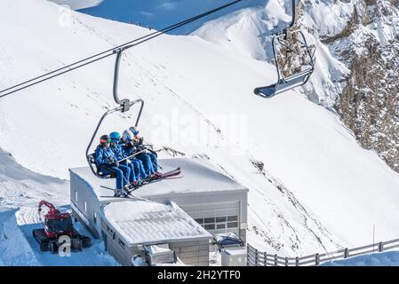 Glacier 3000, Les Diablerets, Schweiz -31. Oktober 2020: Nahaufnahme von Skifahrern, die auf dem Sessellift in großer Höhe sitzen Stockfoto