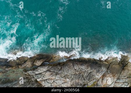 Luftaufnahme der Wellen am Meer Weiße schäumende Wellen auf den Felsen am Meer Draufsicht fantastische Rocky Coast erstaunliche Natur Hintergrund. Stockfoto