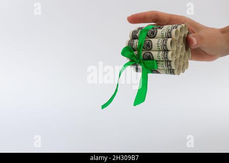 Weibliche Hand hält rollte 100-Dollar-Scheine mit grünem Geschenkband gebunden. Stockfoto