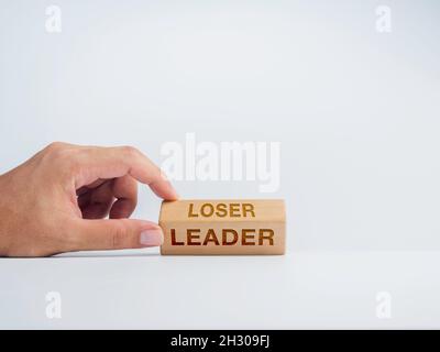 Wechsel zum Anführer. Hand Flip Holzwürfelblöcke für das Ändern von Wörtern von Verlierer zu Führer auf weißem Hintergrund, minimalistischer Stil. Selbstverbesserung, per Stockfoto