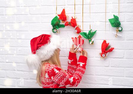 Kind Mädchen Eröffnung kleine Geschenke Überraschungen Adventskalender an der Wand hängen. Frohe Weihnachten und Neujahr. Stockfoto