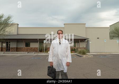 Attraktiver Rüde im weißen Labormantel im Freien Stockfoto