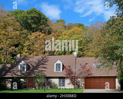 Haus im Ranch-Stil mit Dachfenstern und Garage für zwei Autos, umgeben von Bäumen in Herbstfarben Stockfoto