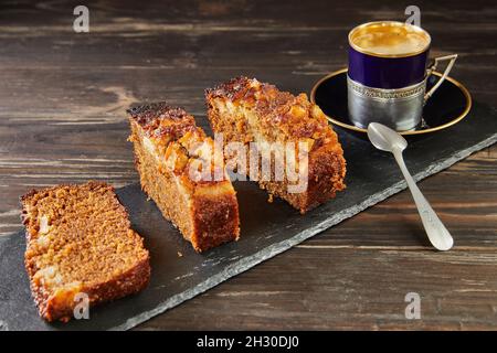 Honigkuchen mit Äpfeln und einer Tasse Kaffee in der Nähe. Französische Gourmetküche Stockfoto