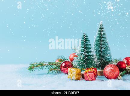 Weihnachten niedliche Bäume auf festlich verschneiten Hintergrund mit Neujahr Spielzeug, Geschenke, helle Kugeln. Festliche Komposition im Winter Stockfoto