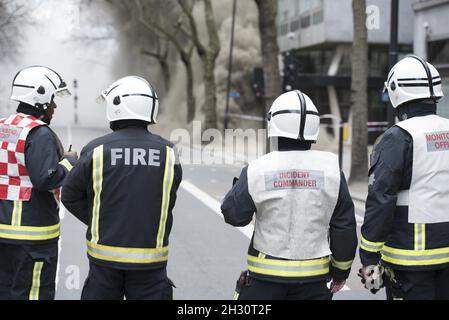 Feuerwehrmann beobachtet, wie Rauch aus einem unterirdischen Kabelbrand auf Kingsway, bei Holborn - London, aufsteigt Stockfoto