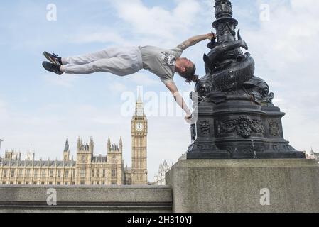 Tim Shieff führt Parkour im Mowgli-Stil während einer Fotowand vor dem Parlament auf. Parkour Pro Tim wird auf der Southbank Meisterkurse durchführen, die von Mowgli inspiriert sind, um die Einführung von The Jungle Book, Jubillee Gardens, Southbank - London zu feiern Stockfoto