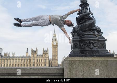 Tim Shieff führt Parkour im Mowgli-Stil während einer Fotowand vor dem Parlament auf. Parkour Pro Tim wird auf der Southbank Meisterkurse durchführen, die von Mowgli inspiriert sind, um die Einführung von The Jungle Book, Jubillee Gardens, Southbank - London zu feiern Stockfoto