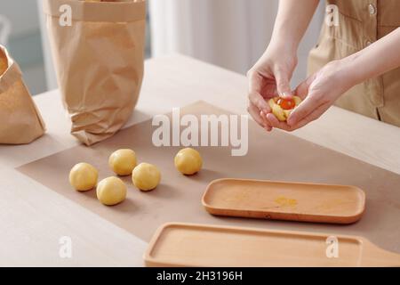 Prozess der Verpackung gesalzenes Eigelb Füllung in Teig bei der Herstellung von traditionellen chinesischen Mondkuchen Stockfoto