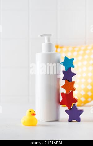 Leere Flasche Baby Hautpflegeprodukt und kleine Spielzeuge stehen auf dem Tisch im Badezimmer Stockfoto