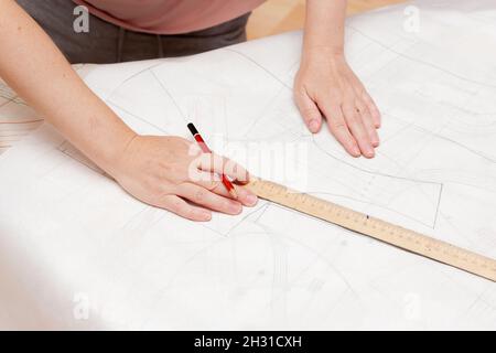 Weibliche Hände machen das Layout des Nähmusters auf Papier Stockfoto