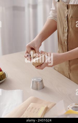 Beschnittenes Bild einer Frau, die Mondkuchen verpackt, die sie zu Hause für das traditionelle Herbstfest in ganz Asien gebacken hat Stockfoto