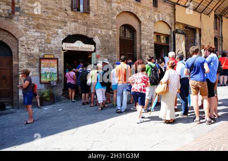 SAN GIMIGNANO, ITALIEN - 30. Jan 2016: An einem sonnigen Tag wartet eine Reihe von Menschen vor der Eisdiele Gelateria Dondoli in San Gimignano Stockfoto
