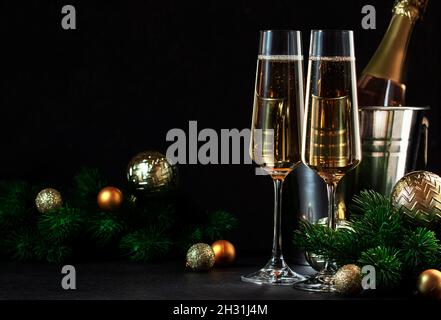 Zwei Sektgläser und goldene weihnachtsdekoration auf schwarzem Hintergrund. Happy New Year oder Merry Christmas Komposition Stockfoto