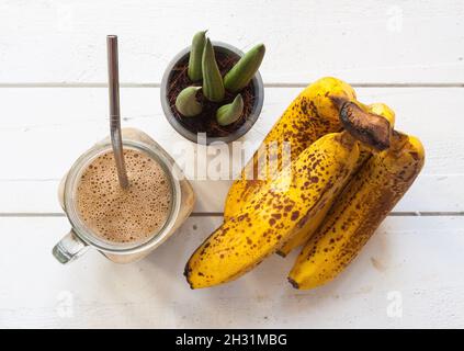 Flache Verlegung eines gesunden Smoothie mit Banane auf eine weiße Holzplatte Stockfoto