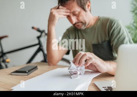 Telearbeiter mit kreativem Block im Heimbüro zerbröckelnde Papierblätter, selektiver Fokus Stockfoto