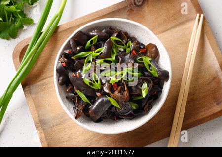 Salat aus chinesischen eingelegten schwarzen Maultierpilzen in einer Schüssel auf weißem Hintergrund. Blick von oben. Stockfoto