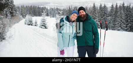 Glücklich reifes Paar zu Fuß Arm in Arm im Freien im Winter Natur, Blick auf die Kamera. Stockfoto