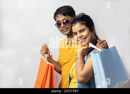 Indisches Paar in gelbem Kleid mit lachenden Einkaufstaschen auf weißem Hintergrund Stockfoto