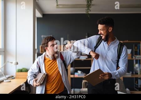 Junger glücklicher Mann mit Down-Syndrom und seinem Mentoring-Freund, der in der Schule Erfolge feiert. Stockfoto