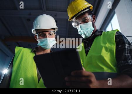 Sichtfeld von Industrieinspektoren mit Gesichtsmasken, die eine allgemeine Überprüfung in der Metallwerkstatt durchführen Stockfoto