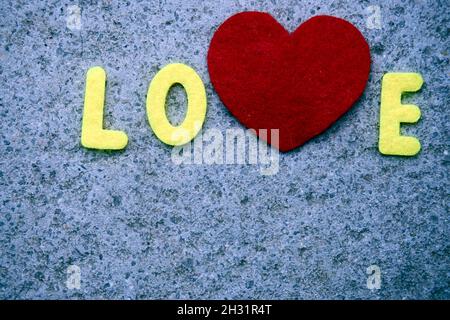 Lettering Love fotografiert mit einem roten Herzen auf einer Steinplatte. Stockfoto