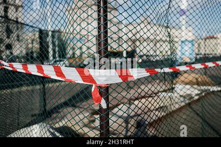 Signalschutzband am Netz. Der Zaun auf der Baustelle besteht aus Signalband. Nahaufnahme des roten und weißen Bandes. Stockfoto