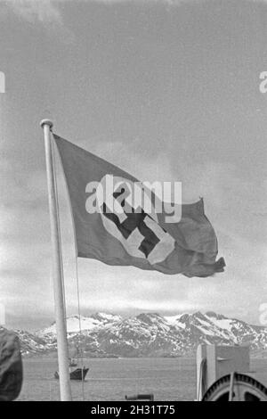 Hakenkreuzflagge im Wind am Heck des Fabrikschiffs Walfang "Jan Wellem" vor einer Inselgruppe im Eismeer der Antarktis, 1930er Jahre. Hakenkreuz Fahne im Wind am Heck des Schiffes "Jan Wellem" des Deutschen walfangflotte vor einem Berg Insel im antarktischen Meer, 1930er Jahre. Stockfoto